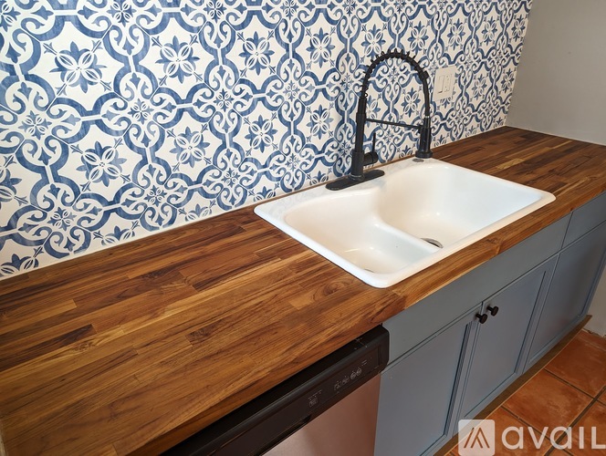 A kitchen with a sink and a wallpapered backsplash.