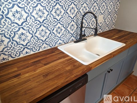 A kitchen with a sink and a wallpapered backsplash.