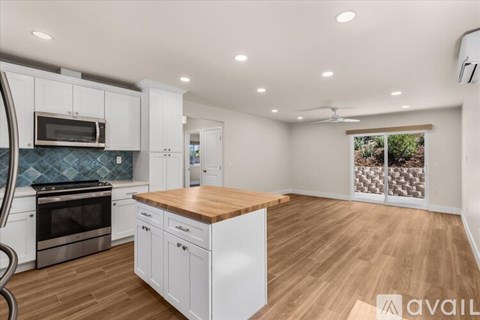 A kitchen with white cabinets and a wooden island.