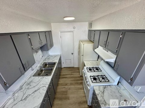 A kitchen with a white counter top and a stove top oven.