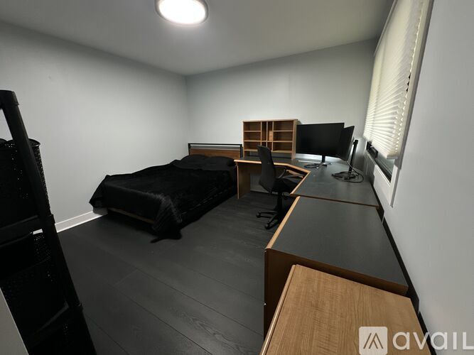 A black leather chair sits in front of a bed with a white comforter and a black pillow.