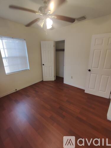A room with a ceiling fan and wooden flooring.