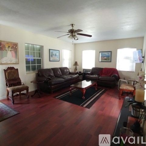 A living room with a brown leather couch and a wooden floor.