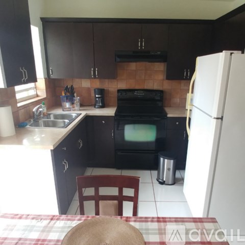 A kitchen with black cabinets and a white fridge.