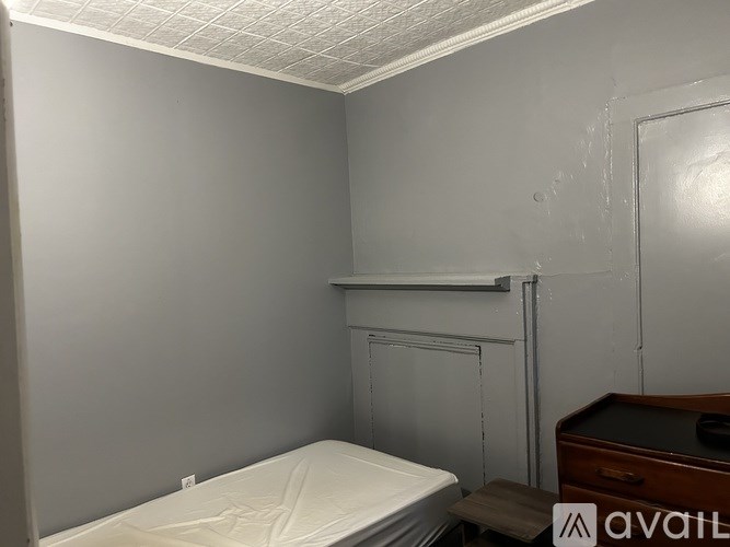 A small bedroom with a bed, desk, and a white ceiling.