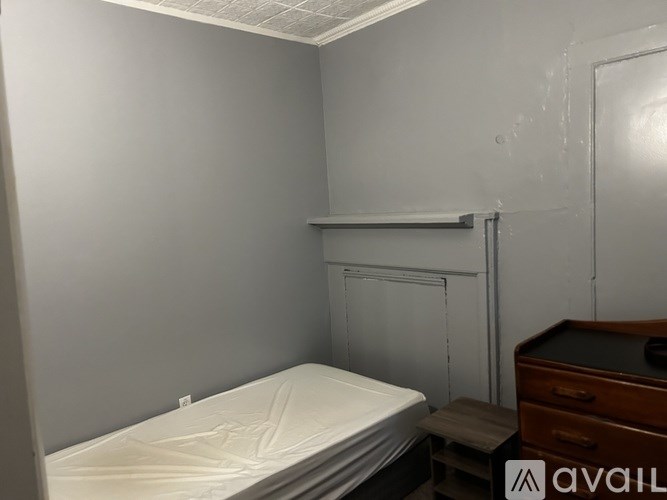 A bedroom with a bed, dresser, and a small shelf.