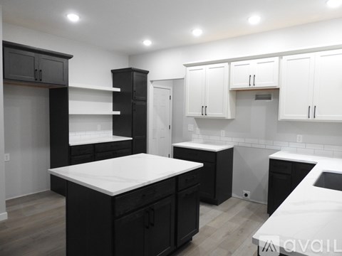 A kitchen with black cabinets and white countertops.