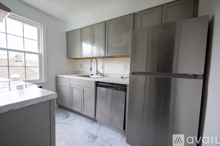 A kitchen with a refrigerator, sink, and cabinets.