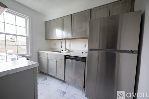 A kitchen with a refrigerator, sink, and cabinets.