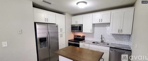 A kitchen with white cabinets and a wooden counter top.