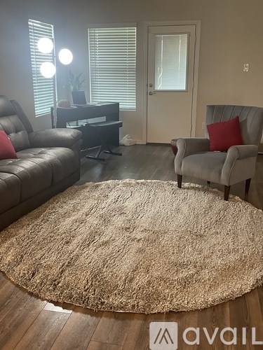 A living room with a brown rug and two grey chairs.