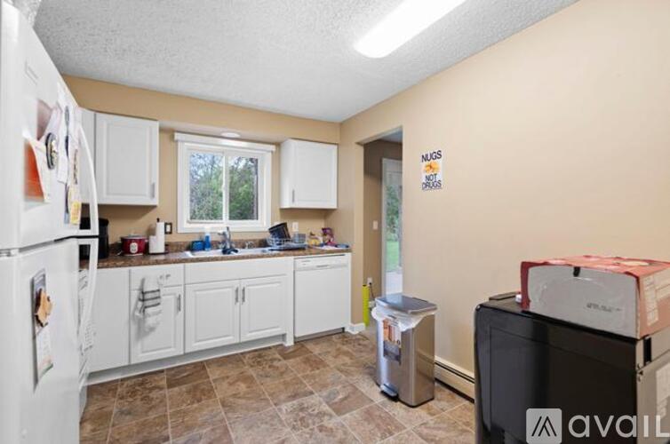 A kitchen with a fridge, a microwave, a dishwasher and a trash bin.