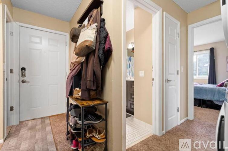 A hallway with a coat rack and a bedroom in the background.