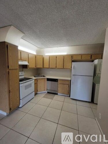 A kitchen with white appliances and wooden cabinets.