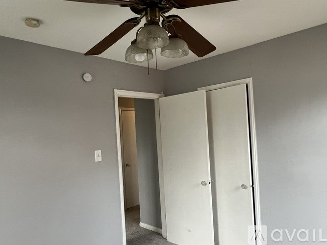 A room with a ceiling fan and two doors.