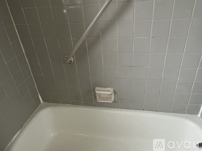 A white bathtub in a bathroom with grey tiles.