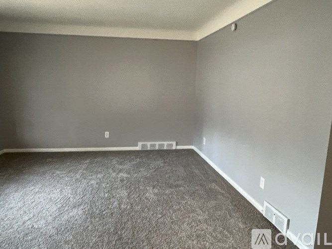 A room with grey carpet and white walls.