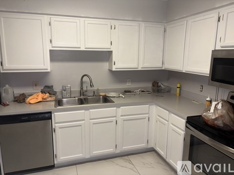 A kitchen with white cabinets and a black dishwasher.