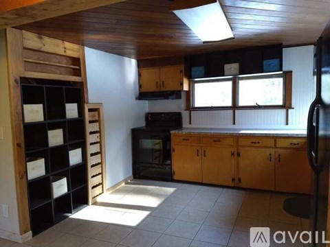 A kitchen with wooden cabinets and a black refrigerator.