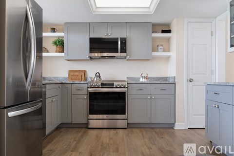 A kitchen with a stainless steel refrigerator and wooden floors.