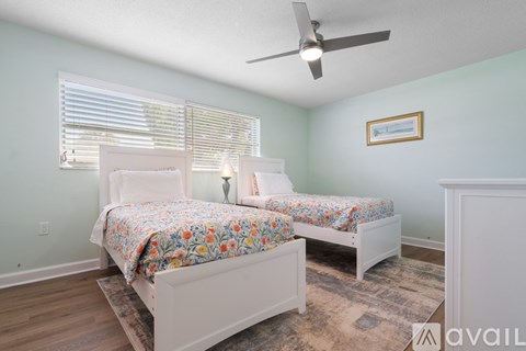 A bedroom with two beds and a ceiling fan.
