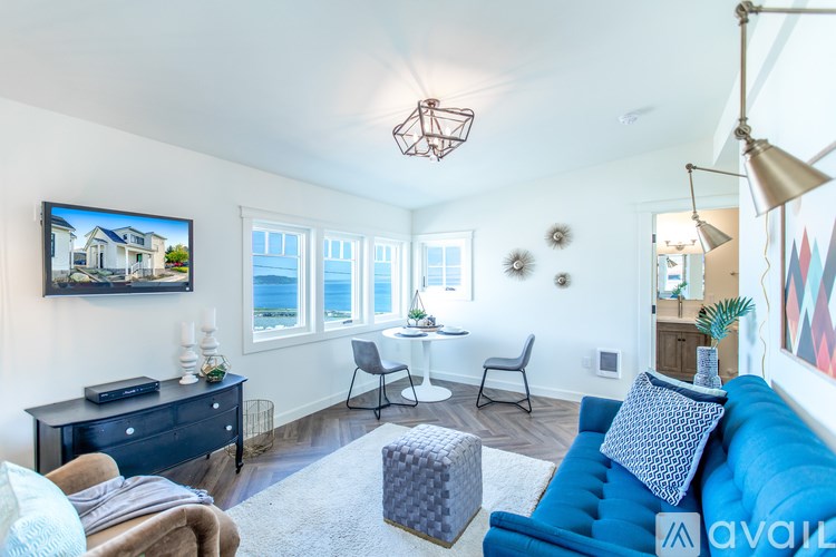 A living room with a blue couch and a television on the wall.
