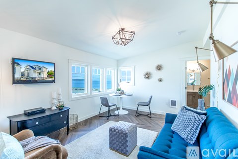 A living room with a blue couch and a television on the wall.