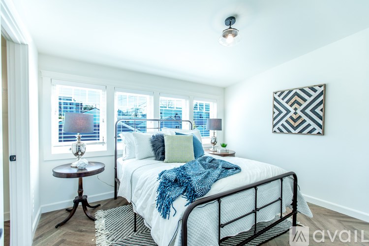 A bedroom with a bed, a table, and a window overlooking a cityscape.