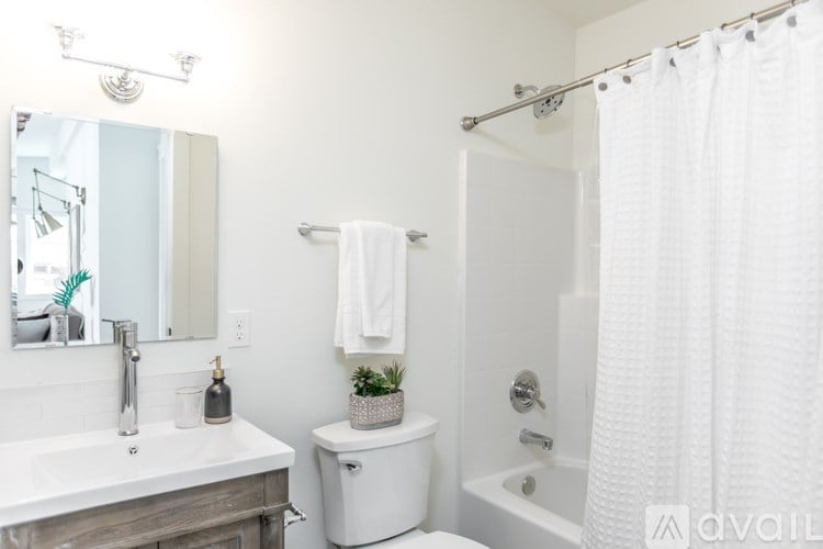 A white bathroom with a toilet, sink, and shower.