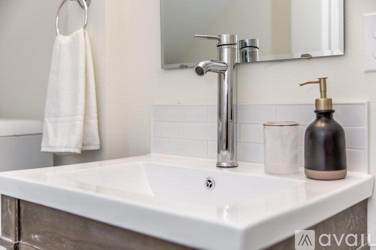 A white sink with a silver faucet and a soap dispenser.