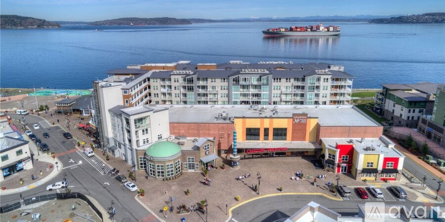 A large building with a green dome is surrounded by a plaza and a body of water.