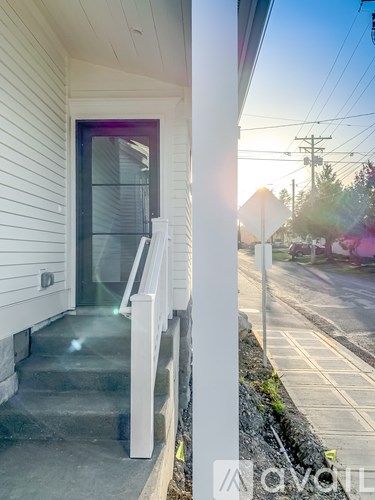 A white house with a purple door and stairs leading to it.