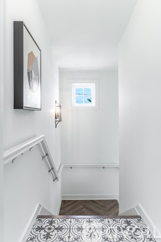 A hallway with a patterned tile floor and a framed picture on the wall.