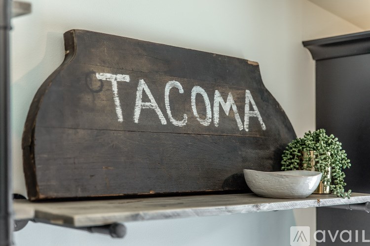 A wooden sign with the word "TACOMA" written on it in white chalk.