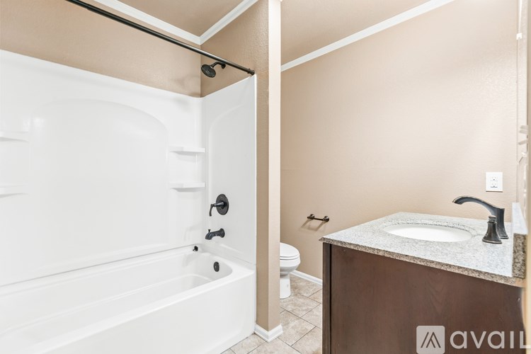 A bathroom with a white tub and brown counter.