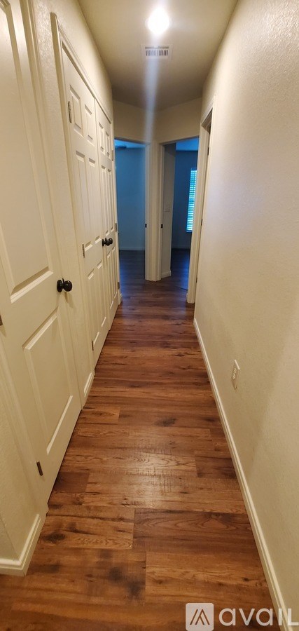 A long hallway with wood floors and white walls.