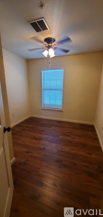 A room with a ceiling fan and wooden flooring.