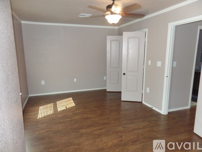 A room with a ceiling fan and wooden flooring.
