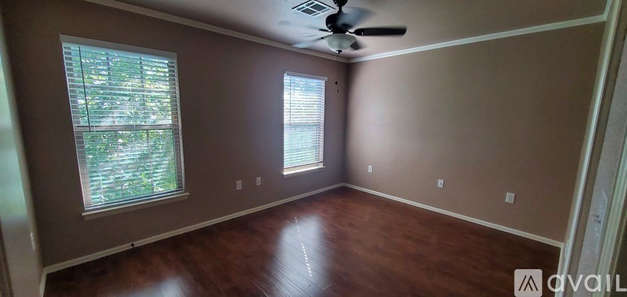 A room with a ceiling fan and two windows.