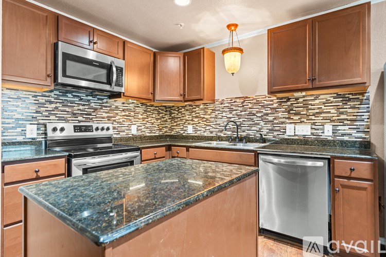 A kitchen with a granite countertop and a tile backsplash.
