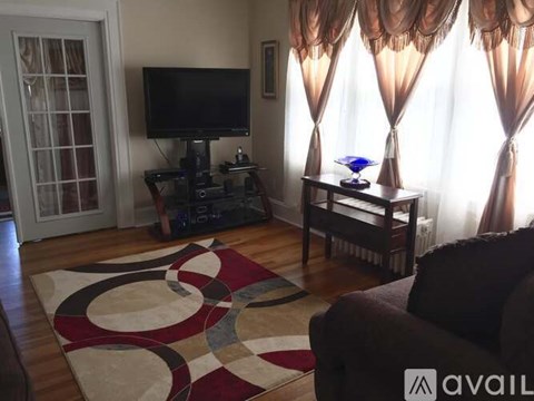 A living room with a television, a couch, and a rug.