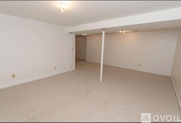 A spacious room with a carpeted floor and white walls.