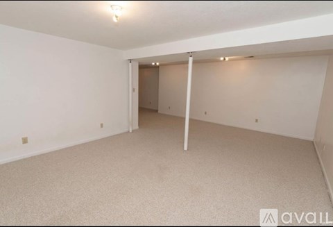 A spacious room with a carpeted floor and white walls.
