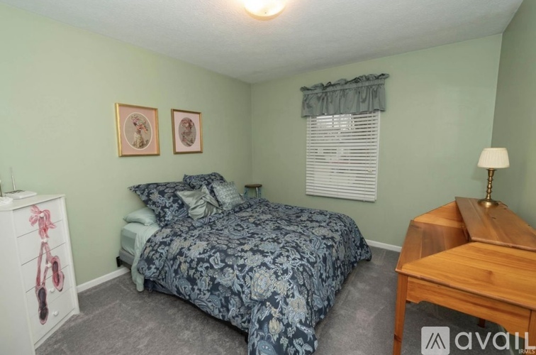 A bedroom with a bed, nightstand, and a dresser with a pink bicycle painted on it.