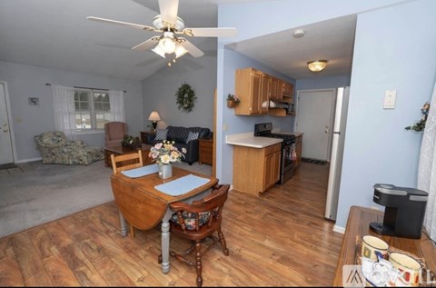 A woman is standing in a kitchen with a dining table and chairs.
