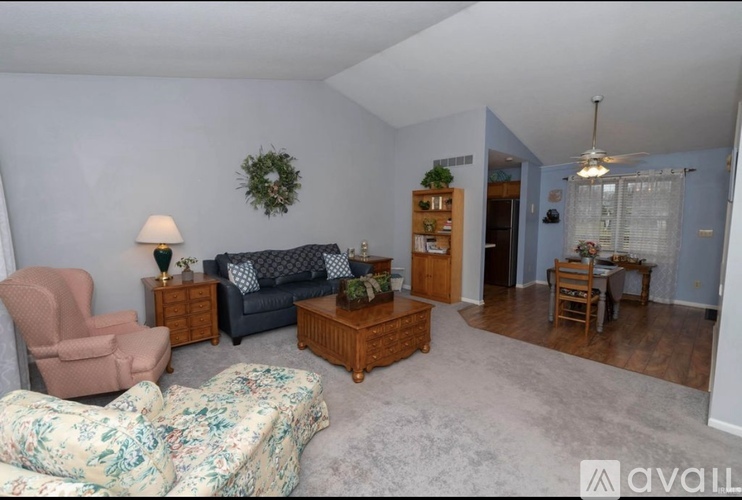 A living room with a couch, chair, and a wreath on the wall.