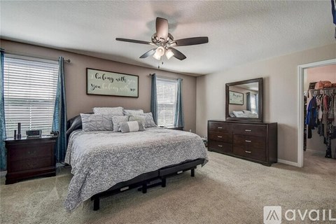 A bedroom with a bed, dresser, and mirror with a ceiling fan.