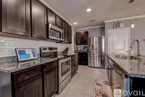 A kitchen with dark brown cabinets and a granite countertop.