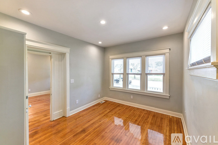 A room with wooden floors and a window with a view of trees.