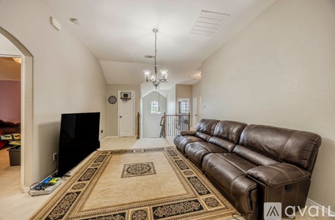 A living room with a brown leather couch and a rug.